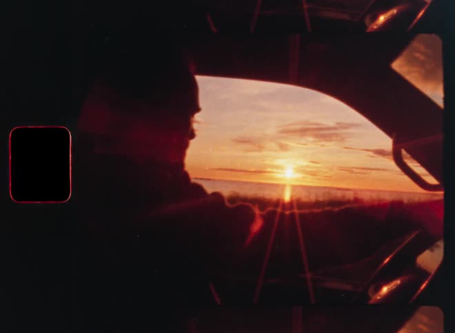 Silhouette of a man driving a car along the coast during a beautiful golden hour sunset, captured on vintage film