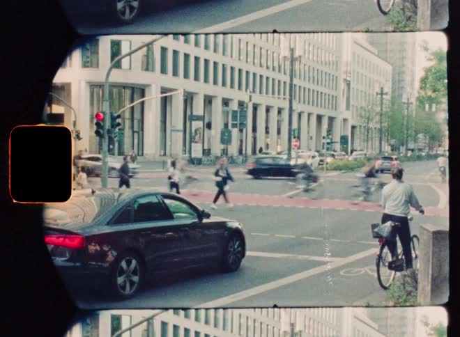 Vintage film time-lapse captures the blurred motion of pedestrians and traffic at a busy urban intersection
