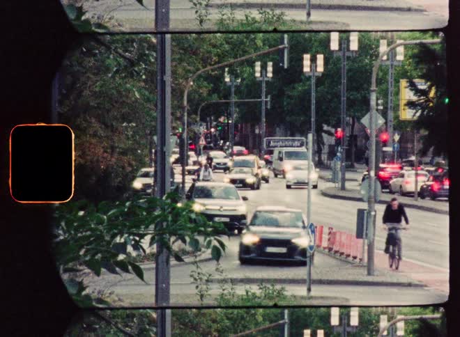 Vintage film captures the bustling traffic of a city street, featuring cars, motorcycles, and bicycles