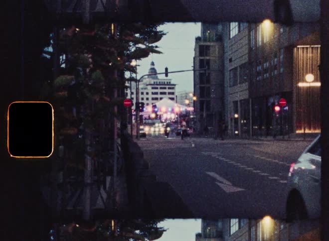 A moody, vintage film-style shot of cars and pedestrians on a city street at night with film grain and light leaks