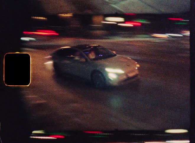 Old film aesthetic captures blurry cars and light streaks on a city street at night
