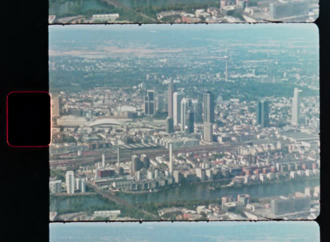 A vintage 8mm film scan captures an aerial, wide-angle view of the Frankfurt city skyline on a sunny day
