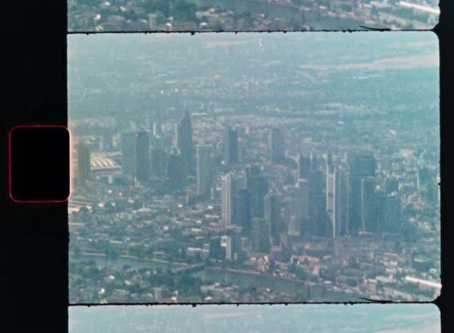 A vintage Super 8 film captures a hazy aerial view of the Frankfurt, Germany cityscape and the Main River
