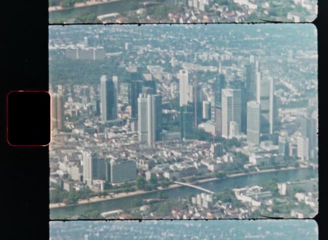 Vintage Super 8 film captures an aerial view of the Frankfurt, Germany cityscape and the Main River on a hazy day