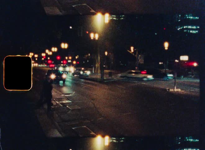 Vintage 8mm film captures the blur of city traffic and pedestrians on a busy street at night