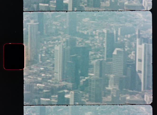 Vintage film scan shows a hazy aerial view of the Frankfurt, Germany cityscape and skyline with a slow zoom