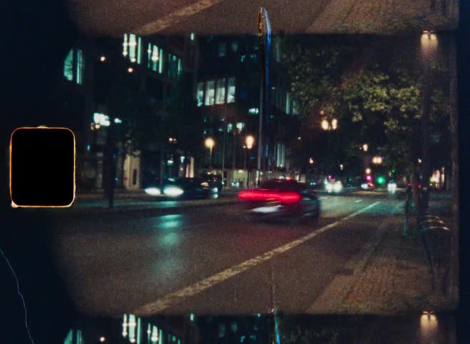 Vintage 8mm film style time-lapse of traffic creating light trails on a city street at night
