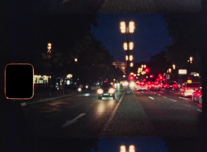 Dreamy vintage film captures the flow of traffic on a bustling city street at night