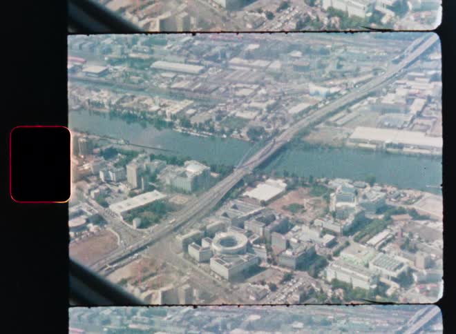 Vintage Super 8mm film captures a nostalgic aerial view of a sprawling city with a wide river and multiple bridges