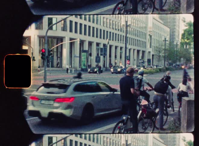 Vintage film captures a bustling city intersection where cars, cyclists, and pedestrians navigate the busy streets