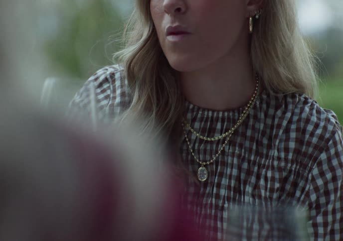 A close-up slow-motion shot of a stylish young woman drinking a glass of red wine outdoors
