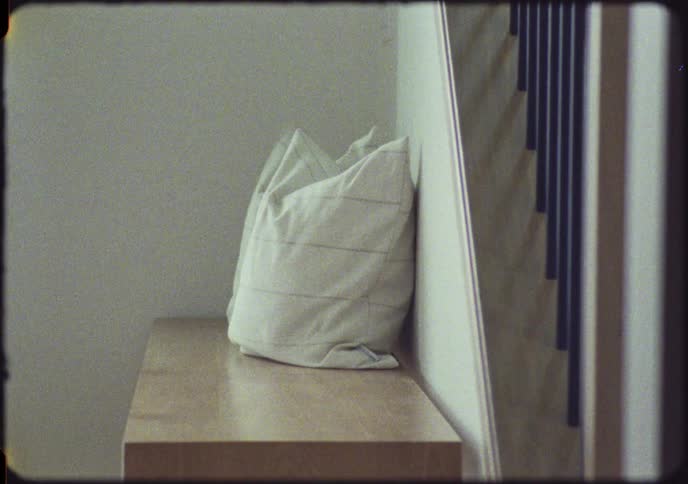 A woman gets up from a bench, grabs her handbag, and leaves in a grainy, vintage-style home video