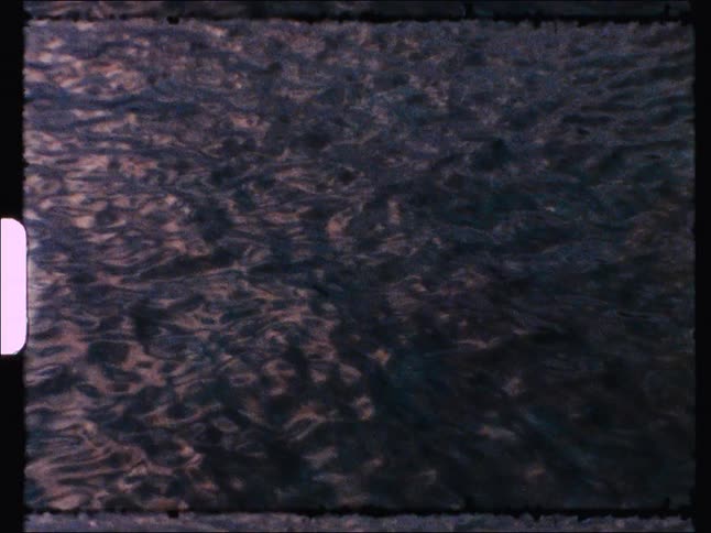 A hypnotic, abstract shot of dark, swirling water captured on vintage film with a rough frame and light leaks