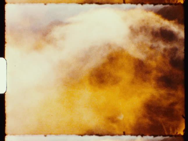 A gritty, abstract view of swirling golden clouds or smoke, captured on a vintage film strip