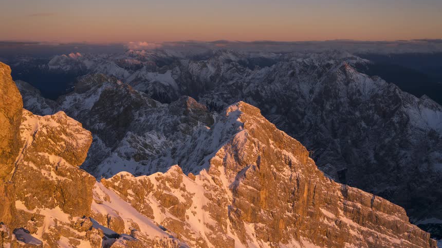 A stunning timelapse captures the golden sunset fading over a majestic, snow-covered mountain range