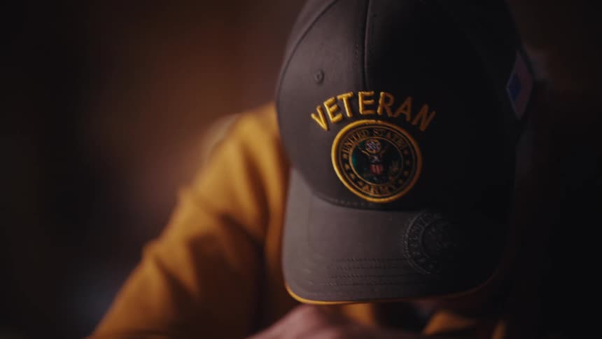A somber, emotional close-up of an elderly US Army veteran looking down with a heavy heart