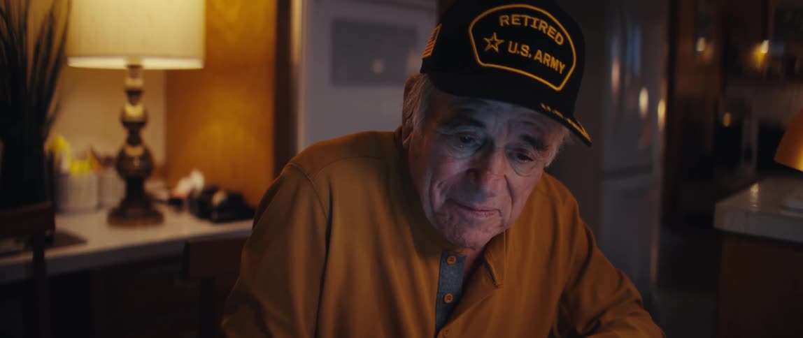A retired U.S. Army veteran diligently balances his budget at the kitchen table late in the evening