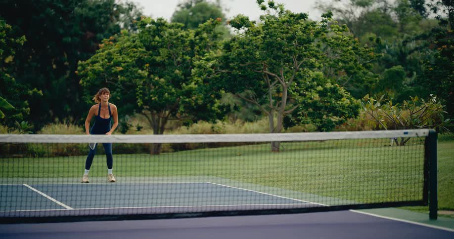 Slow motion of a woman hitting a pickleball volley during a match on an outdoor court