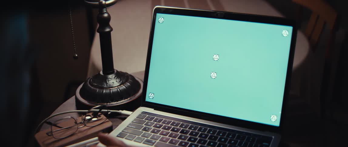 Slow zoom-in over a person's shoulder as they look at a green screen laptop with tracking markers