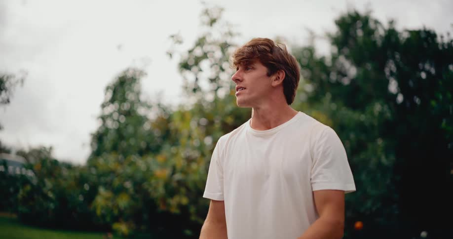 A handsome young man hits a forehand and a backhand while playing pickleball on an outdoor court in cinematic slow motion