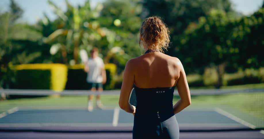 Slow motion shot of a woman in athletic wear playing a game of pickleball with a man on a sunny day