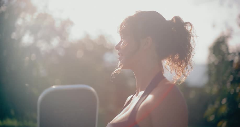 Slow motion footage captures an energetic woman smiling as she plays pickleball outdoors, bathed in warm sunlight