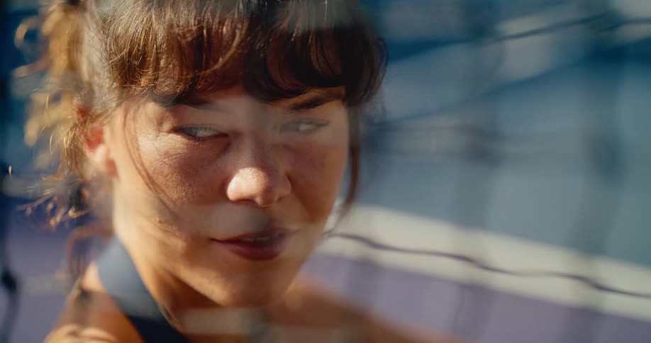 A beautiful young woman with freckles turns her head in slow motion and blissfully soaks up the warm sunlight