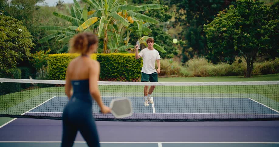 Slow motion shot of a couple playing a friendly game of pickleball on a beautiful outdoor court