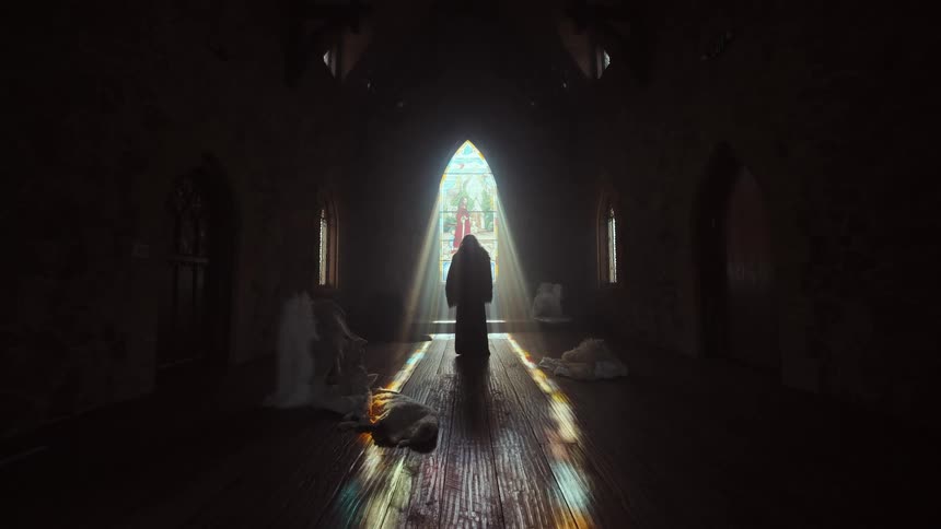 A mysterious robed figure stands silhouetted in a dark, old church as divine light streams through a stained-glass window, with a lamb resting on the floor