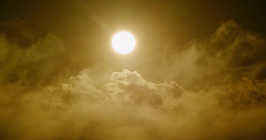 A bright sun hangs in a golden, atmospheric sky as clouds drift slowly past
