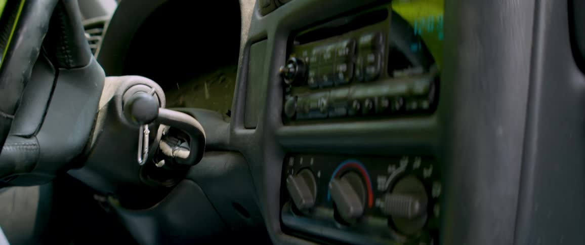 Daylight fades to darkness in a time-lapse from inside a parked car, focusing on the dashboard and keys