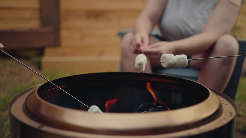 Close-up slow motion shot of marshmallows toasting over a backyard fire pit