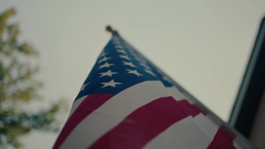 A low-angle close-up shot of the American flag waving slowly in the breeze