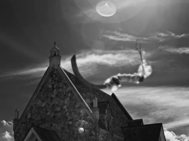 Black and white footage of an abstract animated shape floating across the sky above a stone church