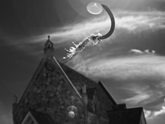 A black and white slow-motion shot of a tattered sickle swinging in front of a spooky stone building