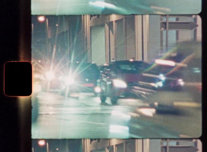 Dreamy, blurred 16mm film footage of bustling city traffic and bright headlights at night