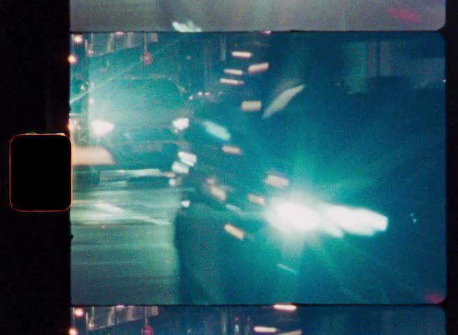 Abstract time-lapse of city traffic at night with streaks of light from headlights, captured on vintage super 8mm film