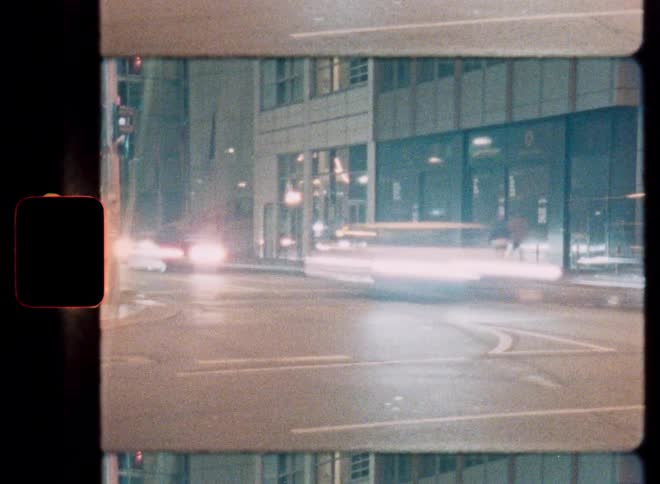 Long exposure shot on vintage film captures the light trails of cars driving through a city intersection at night