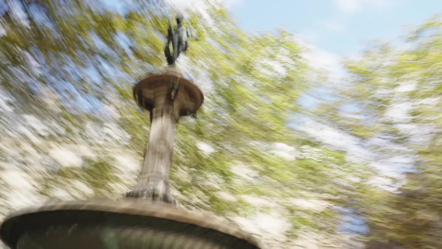 Dizzying artistic hyperlapse circling a historic fountain in a sunlit city square