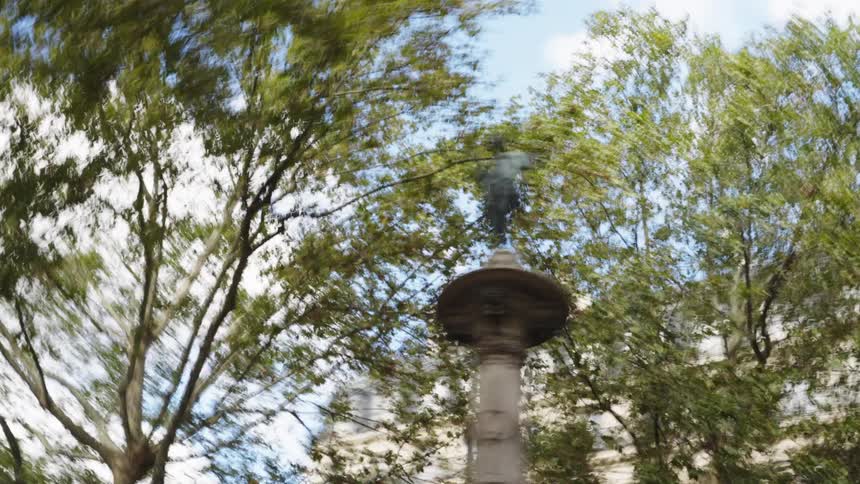 A disorienting, blurry low-angle shot of a classic statue surrounded by trees creates a dizzying visual effect