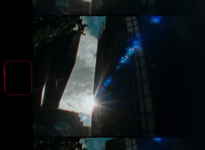 Vintage 8mm film captures a dreamy tilt-up shot of city skyscrapers with a beautiful lens flare