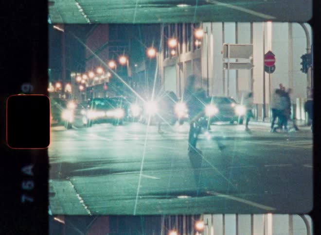 Vintage 8mm film captures the abstract motion of pedestrians and traffic on a city street at night