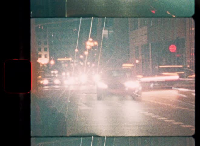 Vintage-style film footage captures a time-lapse of city traffic at night with blurred headlight trails