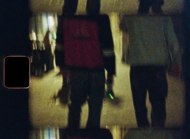 Distorted, grainy vintage-style footage captures a group of young men from behind as they walk down a city street at night