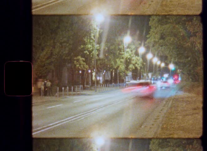 Dreamy, vintage Lomo film captures a long-exposure shot of traffic light trails on a city street at night