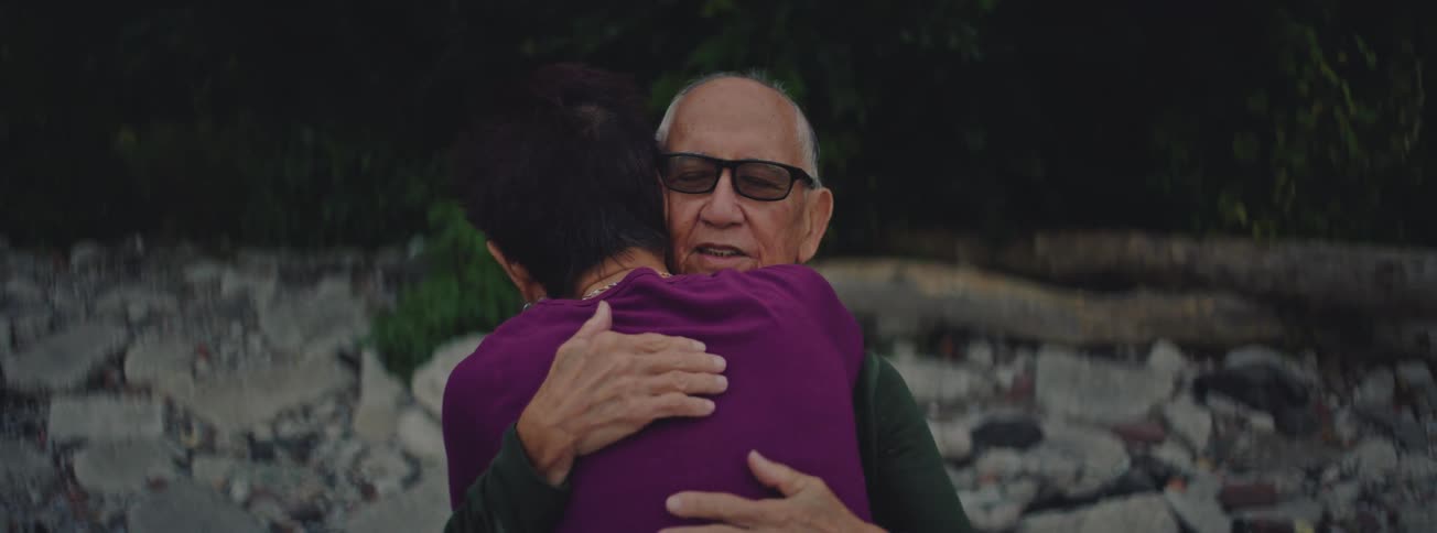A close-up shot captures the tender and loving embrace of an elderly couple as they hold each other close