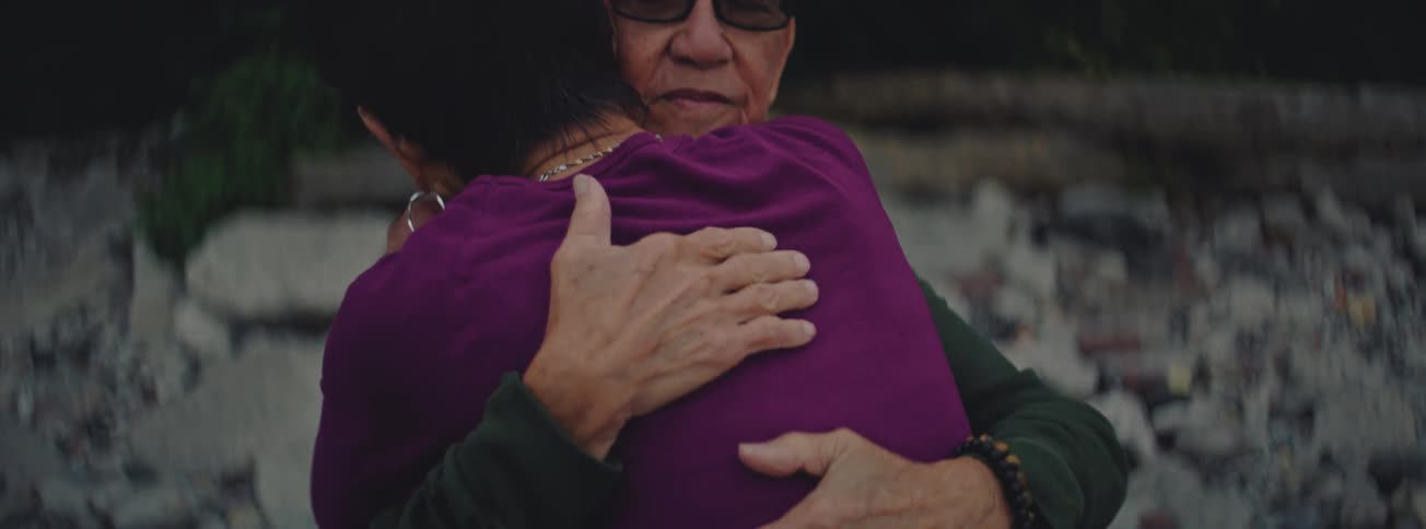 An intimate close-up of an elderly man with glasses holding his partner in a loving embrace