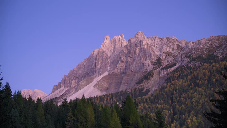 A stunning day-to-night timelapse of a majestic mountain range as the twilight glow fades and stars emerge in the clear night sky