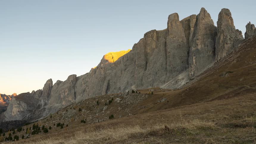 A stunning timelapse captures the golden light of sunset receding from the jagged peaks of the Dolomite mountains