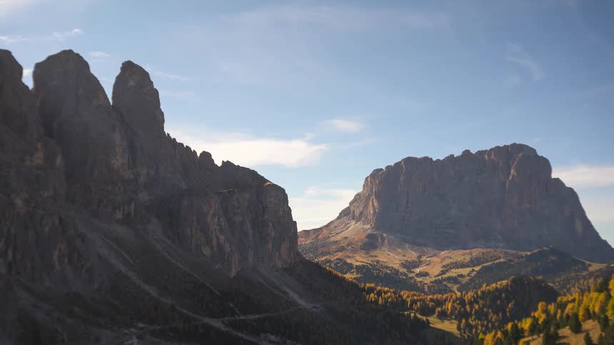A stunning timelapse of clouds and shadows moving across the rugged peaks and golden autumn forests of the Dolomites mountain range